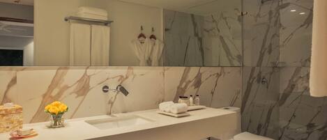 Un baño moderno con tocador de mármol, un espejo grande y una cabina de ducha de vidrio.