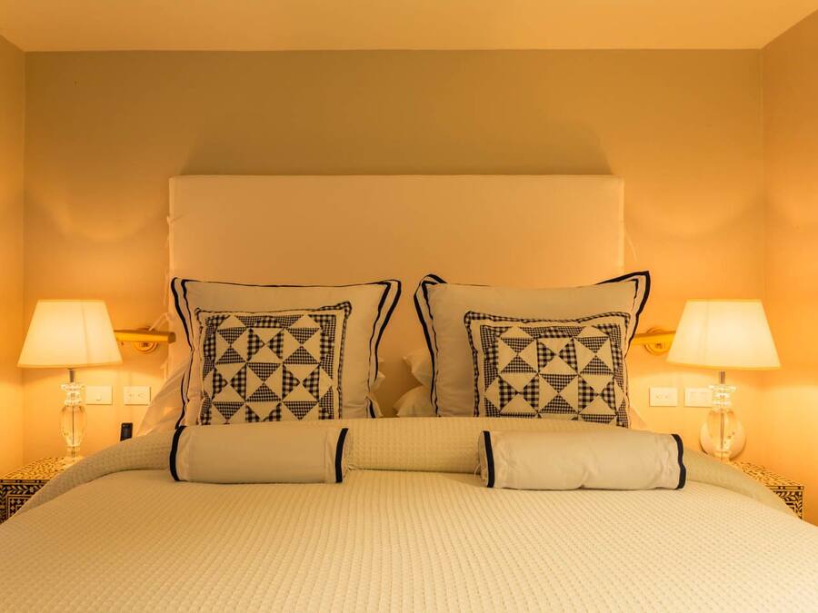 A hotel room with a large bed, two bedside lamps, and a headboard with a geometric pattern.
