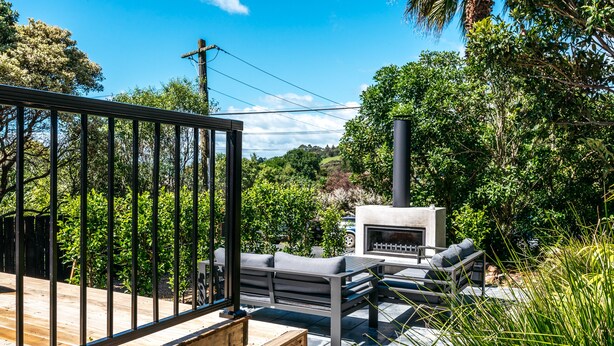 An outdoor patio area with a built-in grill and seating. - Relax on Ridge | 7 seater car included (Oneroa)