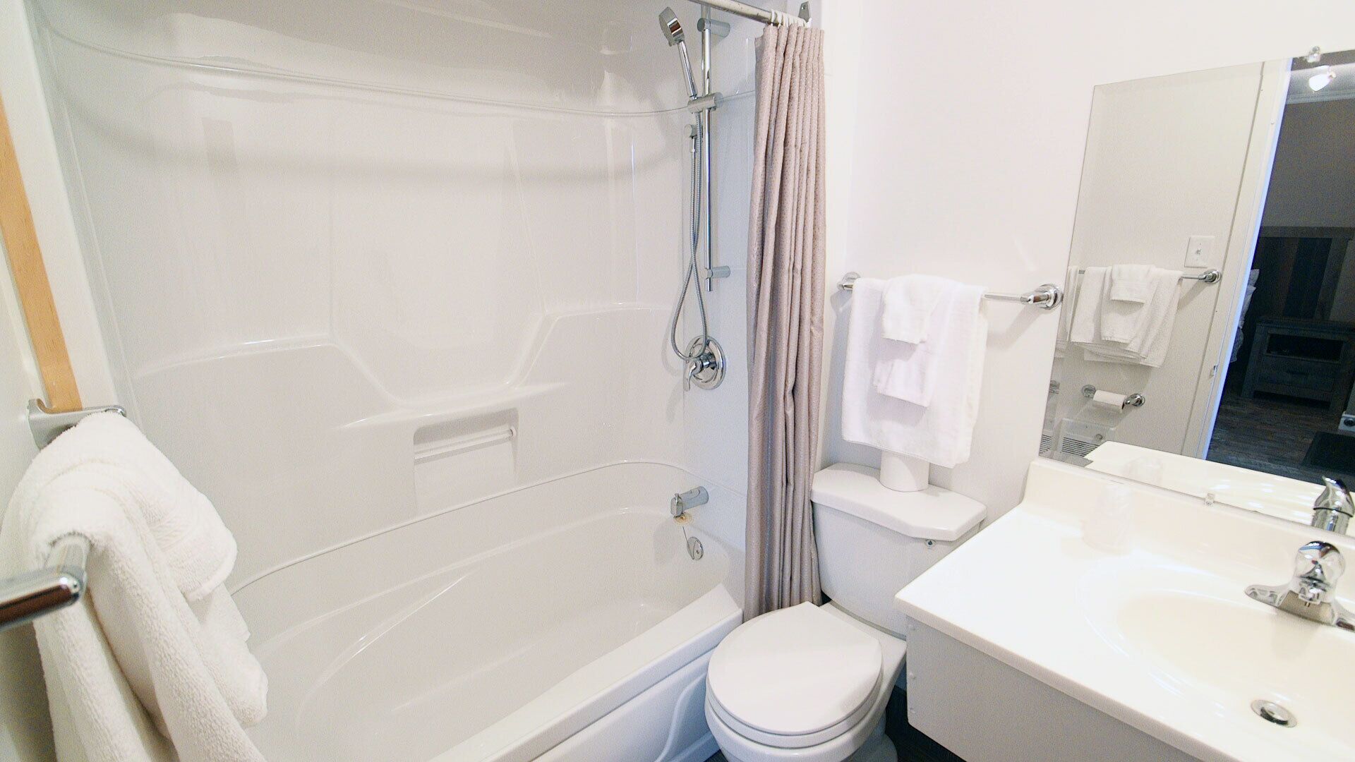 Un bany modern amb dutxa de vidre, un vàter blanc i un lavabo amb mirall.