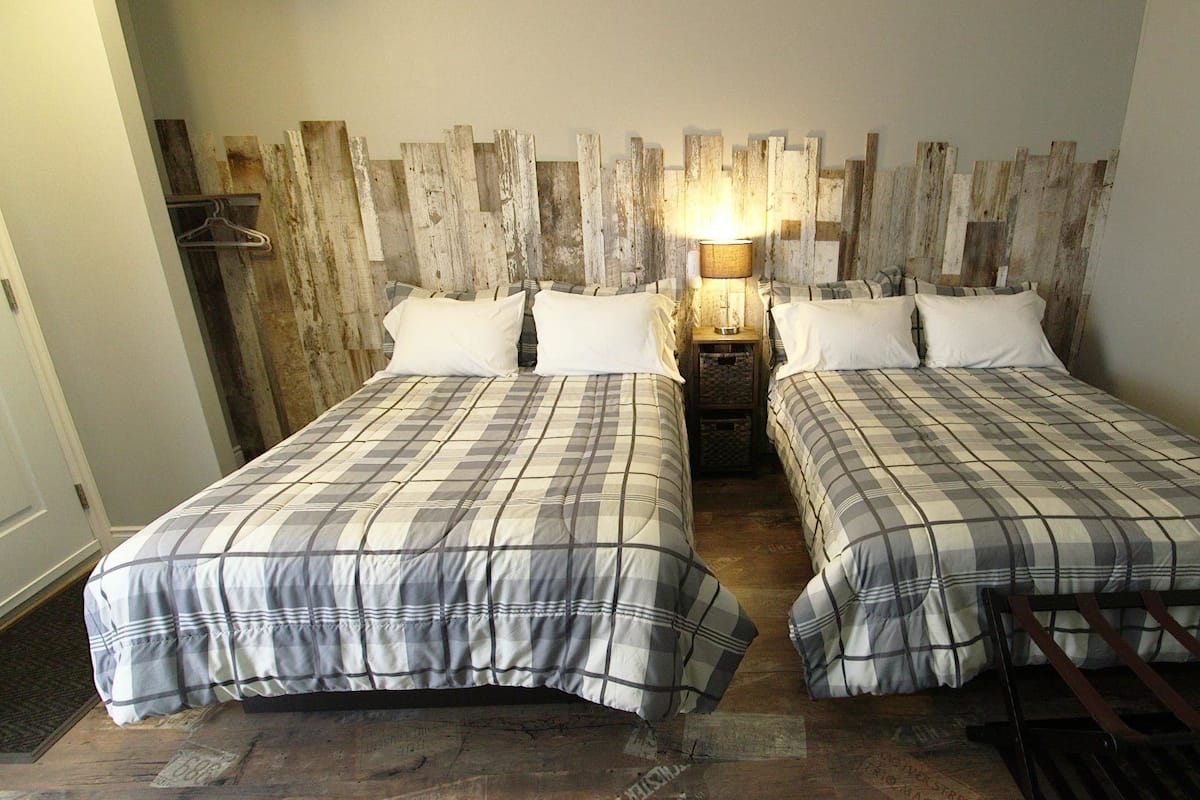Une chambre avec deux lits, une tête de lit en bois, une table de chevet avec une lampe et une chaise.