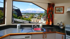 A kitchen with a large window offering a view of a mountainous landscape and a lake.