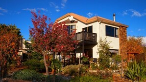 A two-story building with a balcony, surrounded by landscaped gardens and a stone wall.