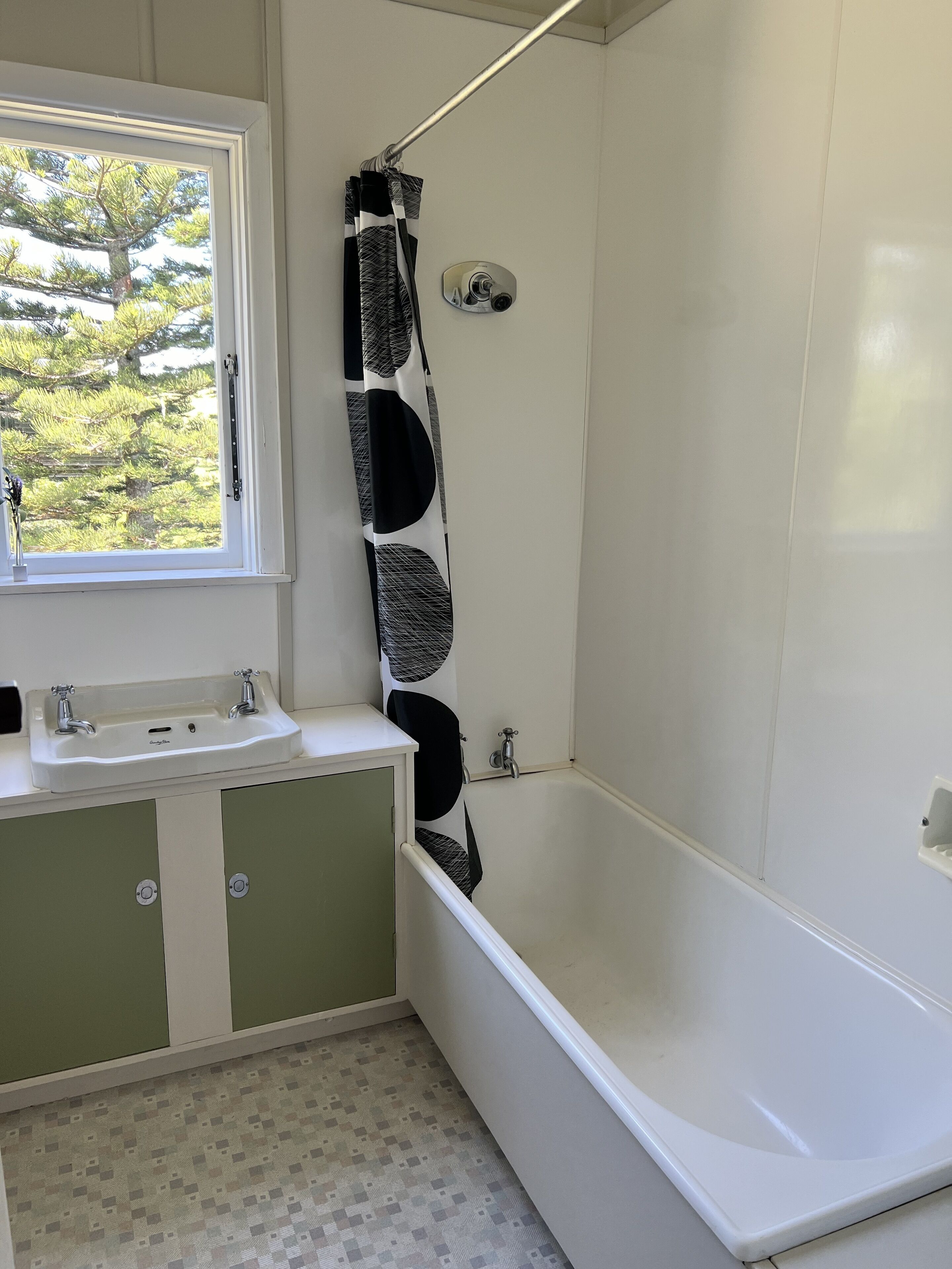 A bathroom with a bathtub, a window, and a sink.
