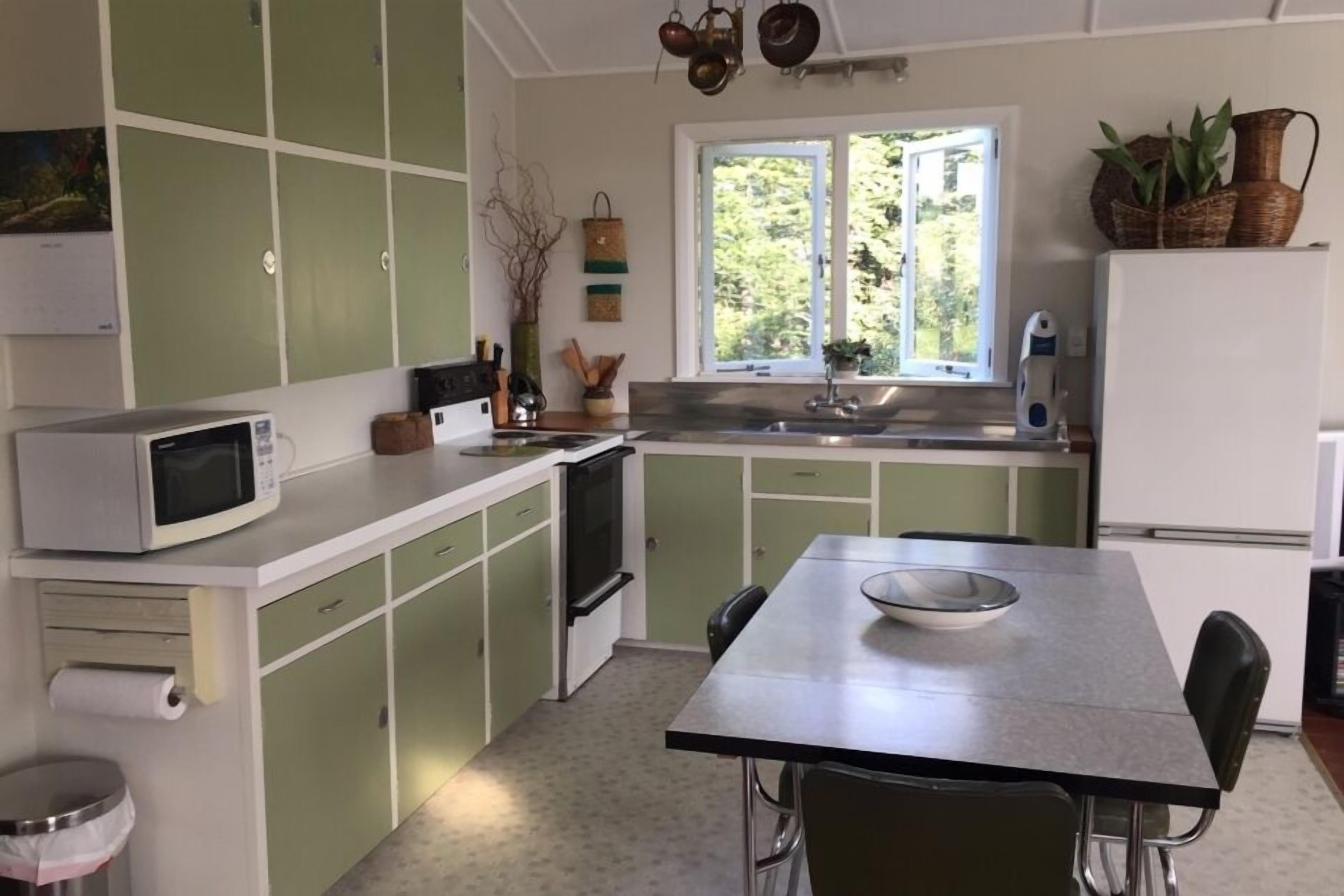 Una cocina compacta con microondas, estufa, pileta y una mesa de comedor con sillas.