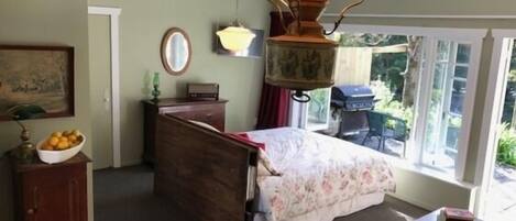 Un dormitorio con cama, mesa, lámpara, ventana y puerta.