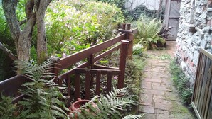 A narrow stone pathway flanked by lush greenery and a wooden fence. - Baubaus House_Holidays house in Cuirone (Vergiate)