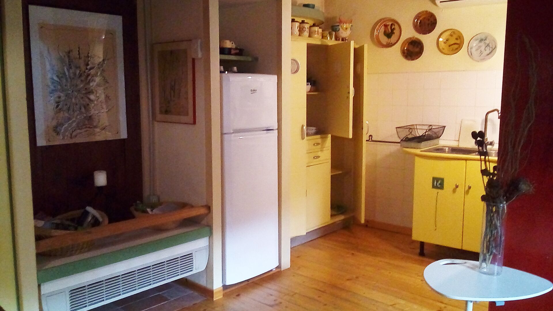 Pieni, käytännöllinen keittiö, jossa on jääkaappi, pesuallas ja pieni ruokapöytä.