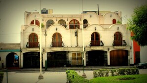 A historic building with multiple arches and balconies, featuring a traditional architectural style. - Hotel Dos Reynas (Characato)