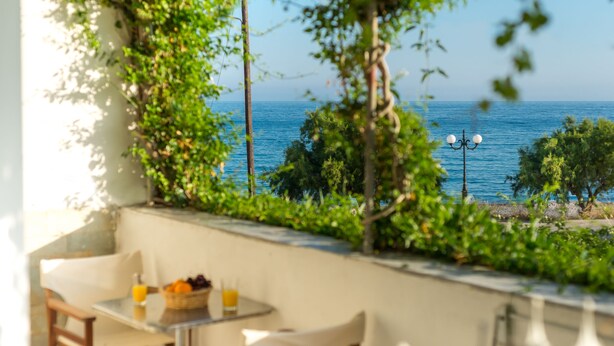 Ein Balkon mit Tisch und Stühlen, der auf ein Gewässer und Grünflächen blickt.