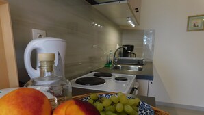 Eine Küche mit Herd, Spüle und Obstschale mit Pfirsichen und Trauben.