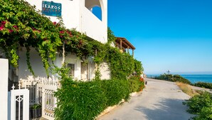 Ein weißes Gebäude mit einem Schild, auf dem "IKAROS VILLAS" steht, und Blick auf das Meer.