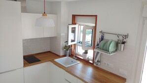 A modern kitchen with white cabinets, a wooden countertop, a white sink, and a pendant light.