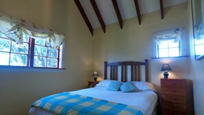 A bedroom with a bed, a nightstand, a dresser, and two windows with curtains. - The Stablehand Quarters at Gunyah Country Estate by Mt Hutt (Methven (Mt Hutt))
