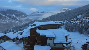 Ein verschneites Bergdorf mit Holzhäusern und Blick auf die umliegenden Berge.