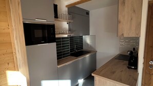 Eine kleine Küche mit Mikrowelle, Spüle und Holzschränken.