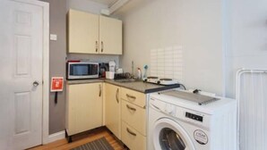 A compact kitchen with a microwave, sink, and washing machine. - Small Cozy studio with WiFi & cable (Southampton)