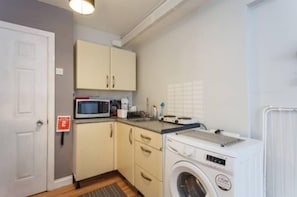 Convenient laundry facilities with a washing machine, microwave, and countertop space.