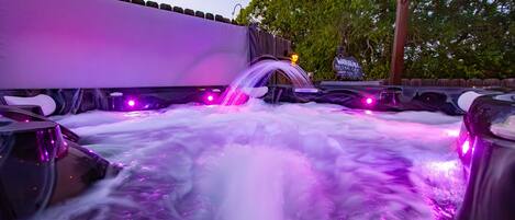 A hot tub area with a water feature and purple lighting.
