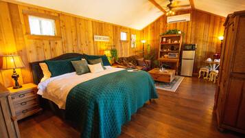 A cozy room with a bed, a wooden dresser, a small table, and a kitchenette area.