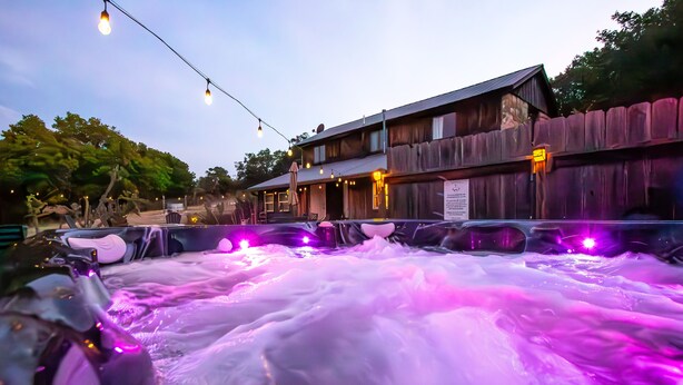 A hot tub area with wooden walls and string lights. - A Barn at the Quarry (Fredericksburg)