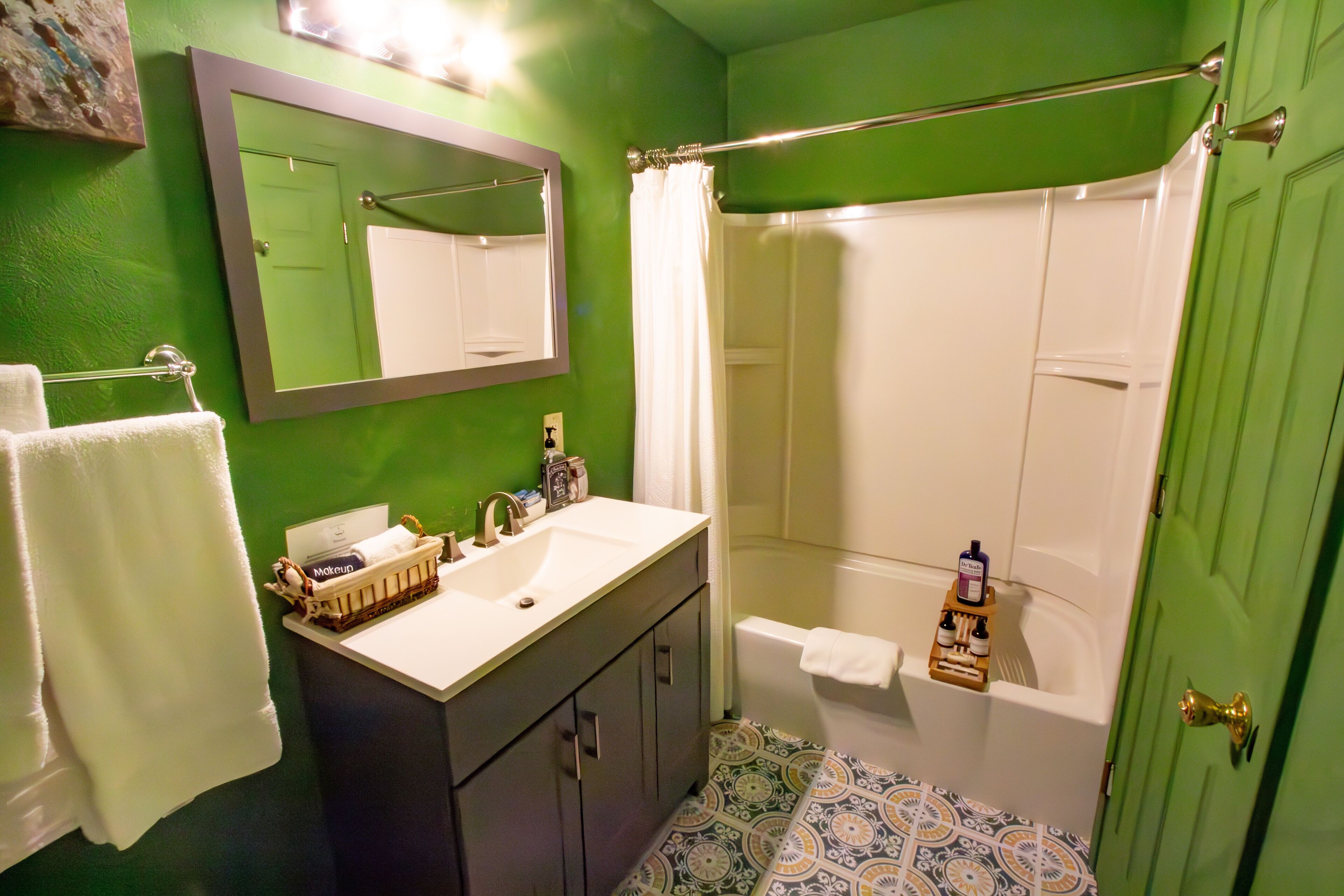 A bathroom with a green wall, a white sink, a mirror, a shower curtain, and a door.