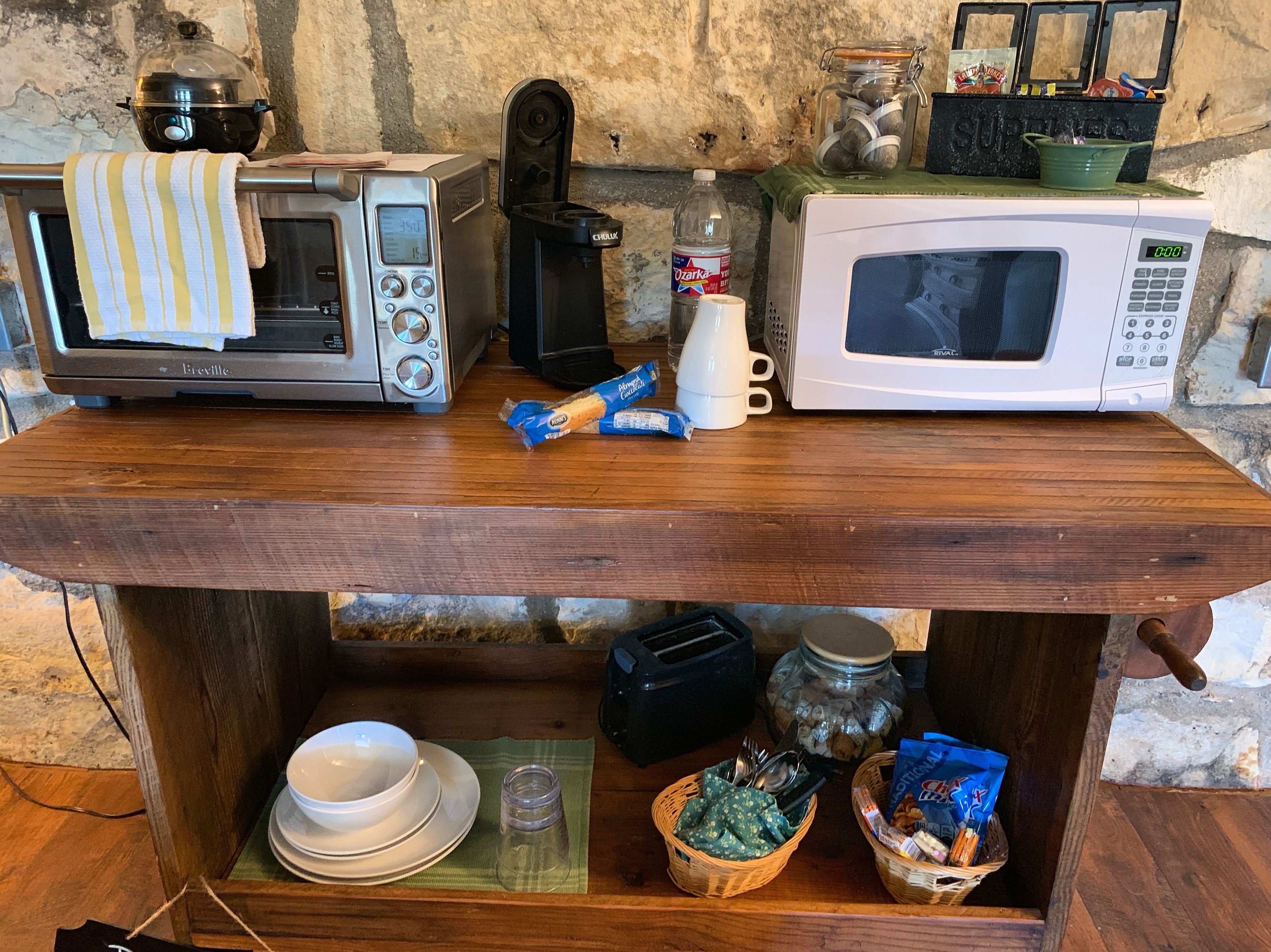 Una encimera de cocina con un tostador Breville, una cafetera, un microondas blanco y varios utensilios de cocina.