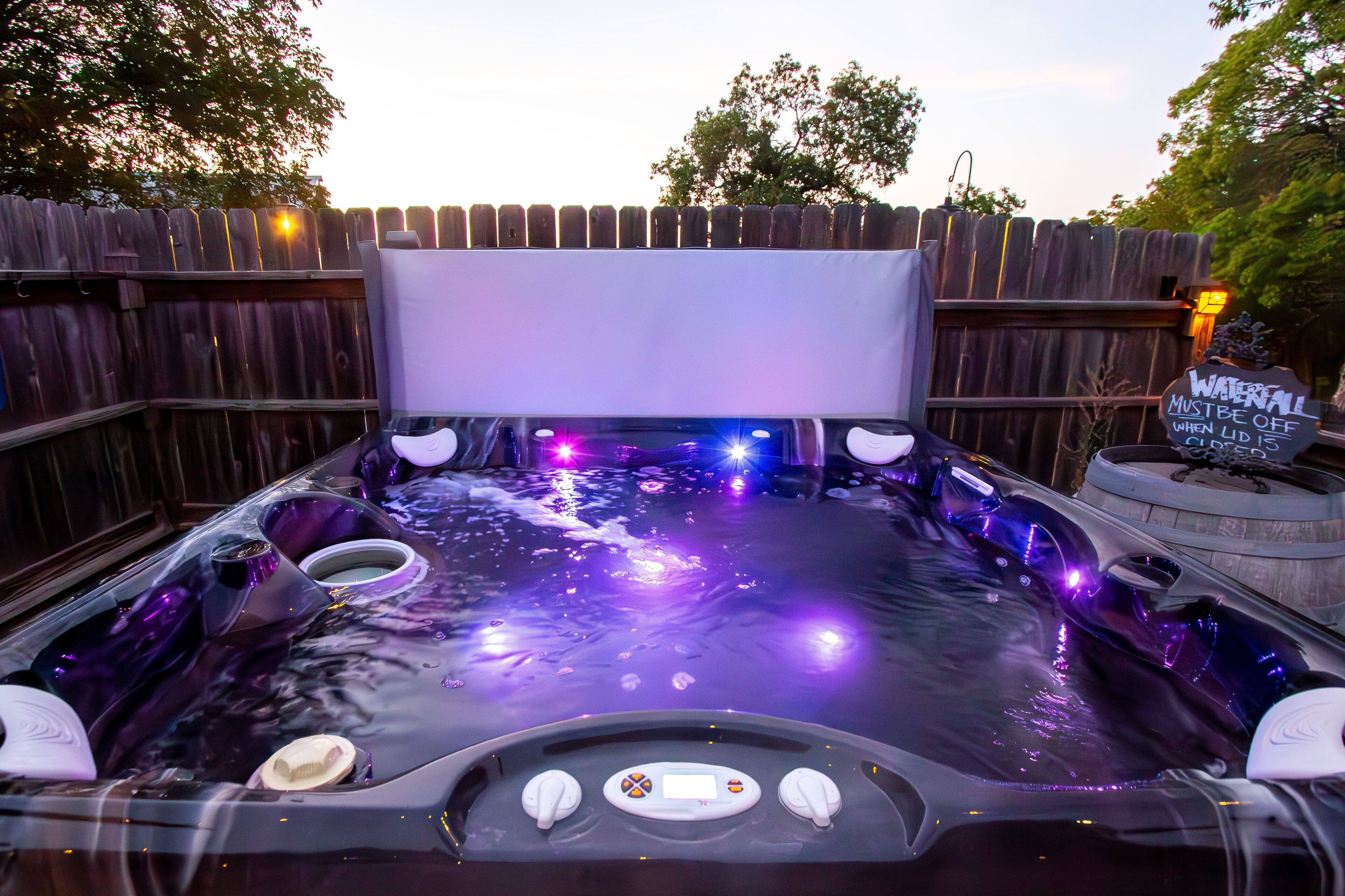 A hot tub with a control panel and a sign indicating it must be turned off when not in use.
