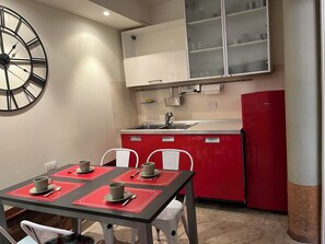 Eine kleine Küche mit rotem und weißem Farbdesign, einem Spülbecken, einem Herd und einer Uhr an der Wand.