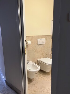 Ein Badezimmer mit einem Bidet, einer Toilette und einem Handtuchhalter.