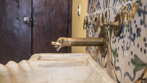 A bathroom with a vintage sink, a wooden door, and a tiled wall with floral patterns.