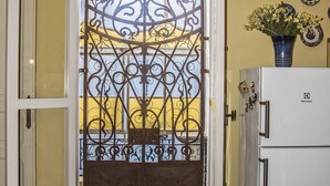 A kitchen with a white refrigerator, a dining table with a placemat, and a decorative metal gate.