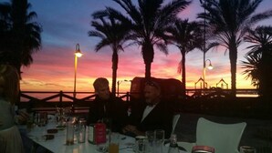 Ein Tisch für zwei Personen in einem Restaurant mit Blick auf den Sonnenuntergang und Palmen.
