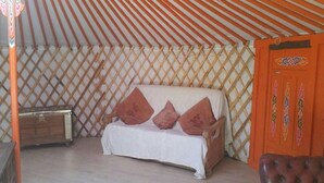 Ein Zimmer mit einer Couch, einem Holzkabinett und einer Tür mit dekorativen Mustern.