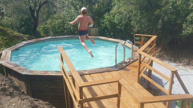 Eine Holzterrasse mit Whirlpool und einer Leiter zum Hineinsteigen.