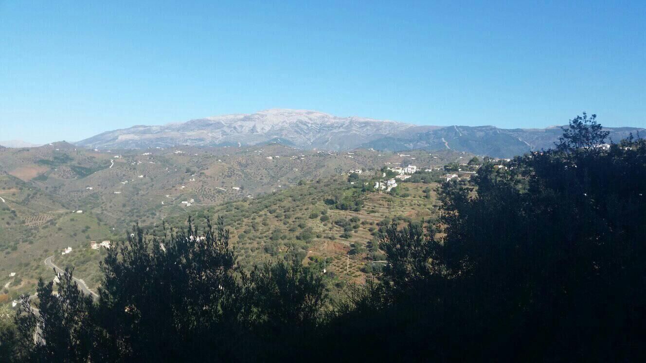 A mountainous landscape with scattered buildings and a clear sky.