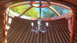 Eine traditionelle Jurte mit einem Bett, einer Holzkiste und einer hängenden Lampe.