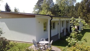A white building with a covered patio area, outdoor seating, and a garden. - Guesthouse built on the owner's plot. close to beach, shop and golf course. (Trelleborg)