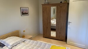 A bedroom with a bed, a wardrobe, a bedside table, a lamp, and a framed picture on the wall. - Guesthouse built on the owner's plot. close to beach, shop and golf course. (Trelleborg)