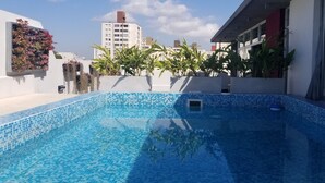 A rooftop swimming pool with blue mosaic tiles, surrounded by white walls and potted plants. - Palermo Market Luxury apartaments (Buenos Aires)