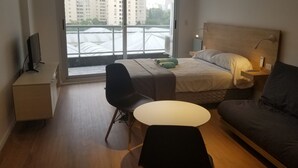 A modern hotel room with a bed, a sofa, a desk, and a chair. - Palermo Market Luxury apartaments (Buenos Aires)