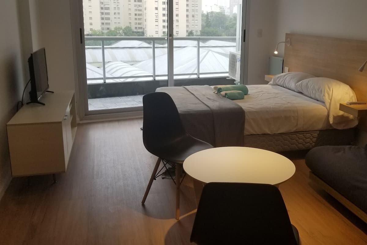 A modern hotel room with a bed, a sofa, a desk, and a chair.