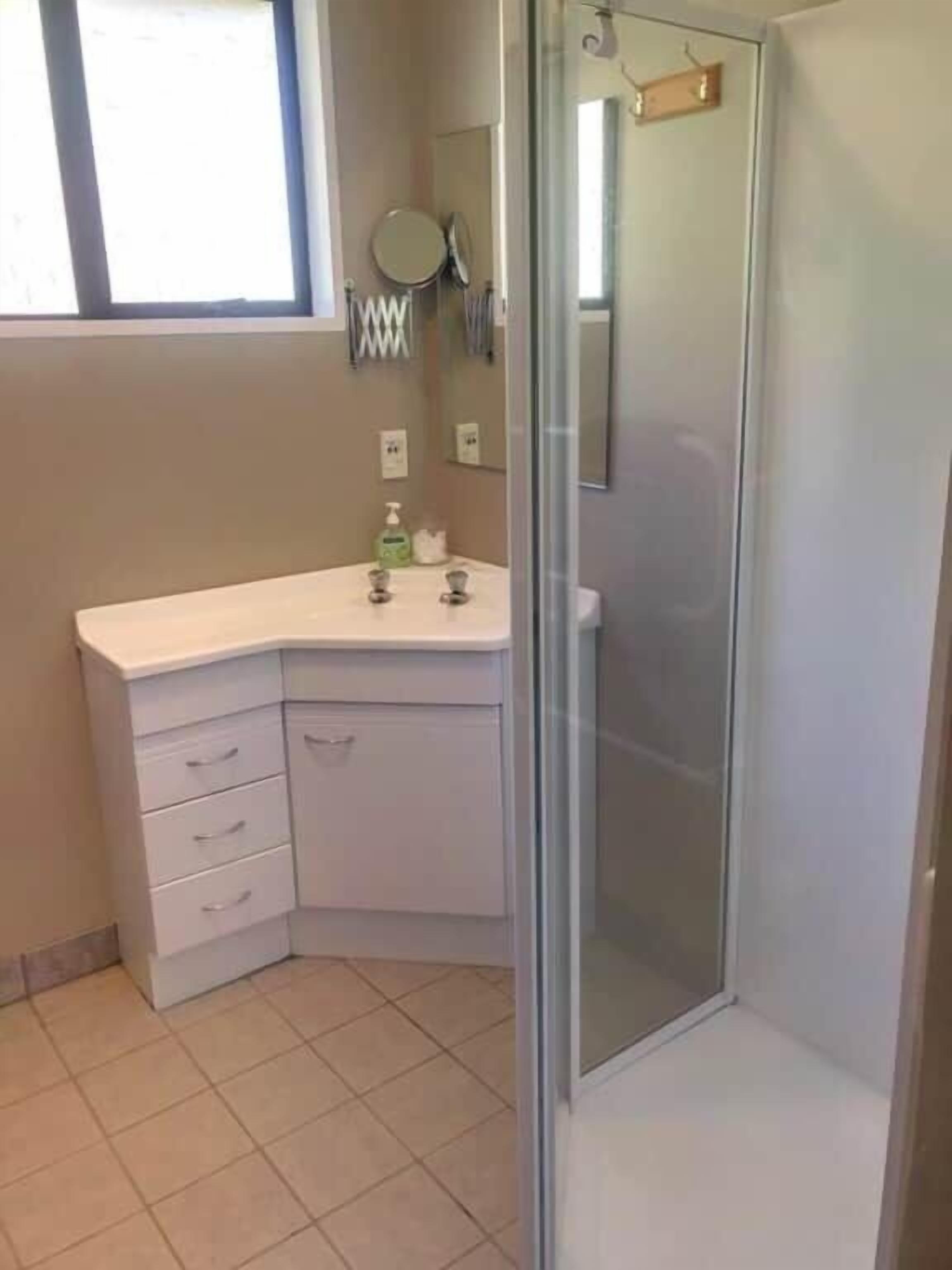 A bathroom with a shower, a sink with a mirror, and a toilet.