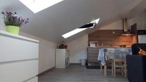 Une cuisine moderne dotée d’une lucarne, un coin repas avec une table et des chaises, et un petit réfrigérateur.