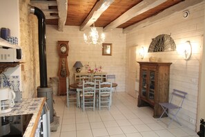 Cozinha rústica com mesa de madeira, cadeiras, relógio e armário.