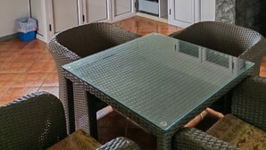 Eine kompakte Küche mit weißen Schränken, einem eingebauten Ofen und einem Essbereich mit Korbstühlen und einem Glastisch.