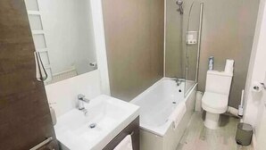 Un baño moderno con tocador doble, bañera, inodoro y ducha.