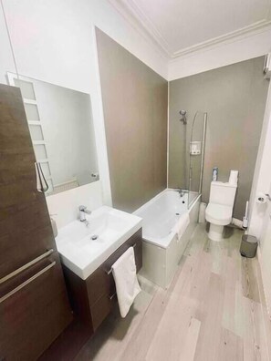 Een moderne badkamer met een dubbele wastafel, een badkuip, een toilet en een douche.