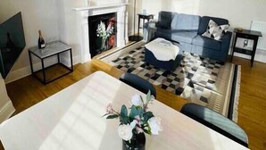 Een moderne woonkamer met een open haard, een bank, een salontafel en een eethoek.