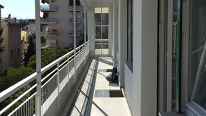A balcony with white railings, a tiled floor, and a view of neighboring buildings. - Ruby Apartment 3 (Sanremo)